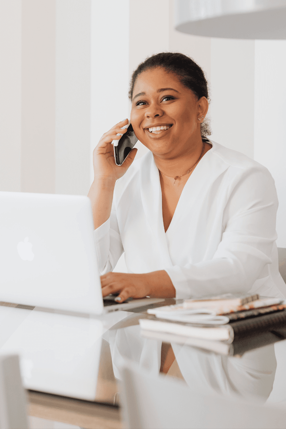 Woman talking on the phone while sitting at a laptop